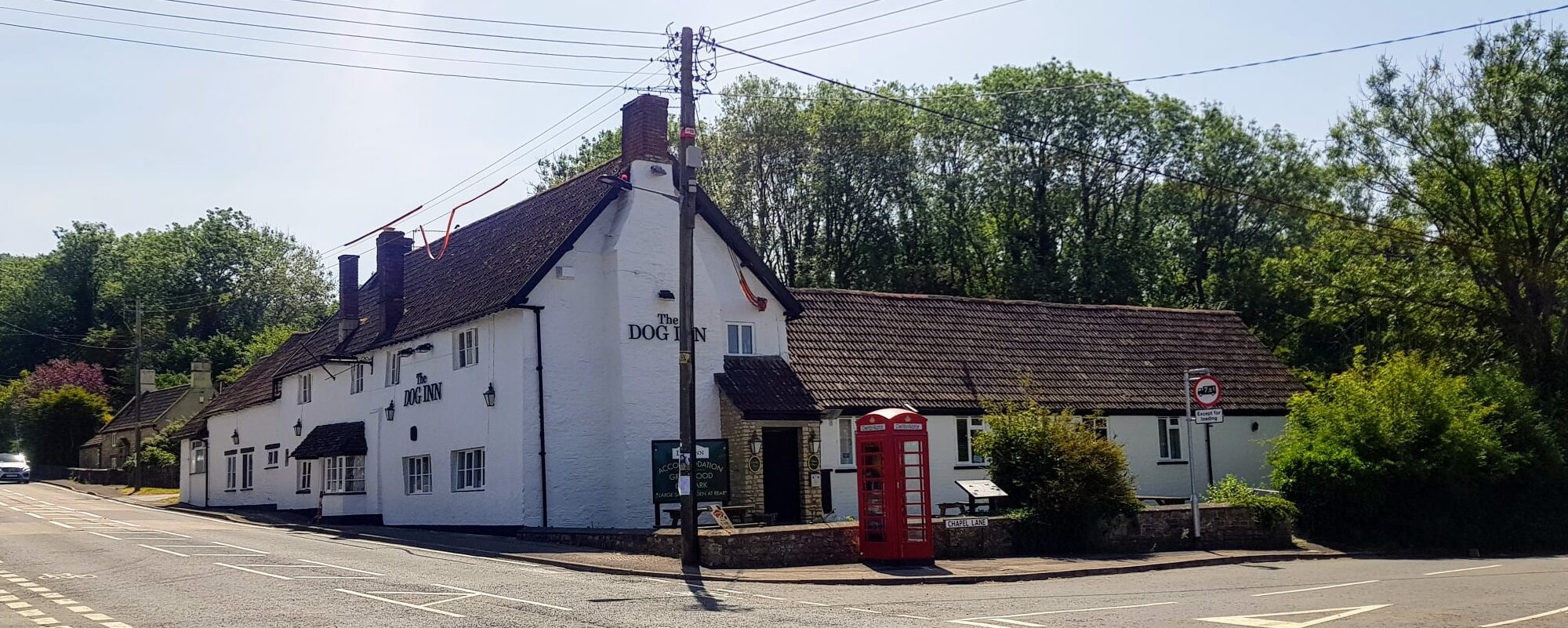 The Dog Inn at Old Sodbury — a white-painted, 500-year-old village pub beside a red telephone box